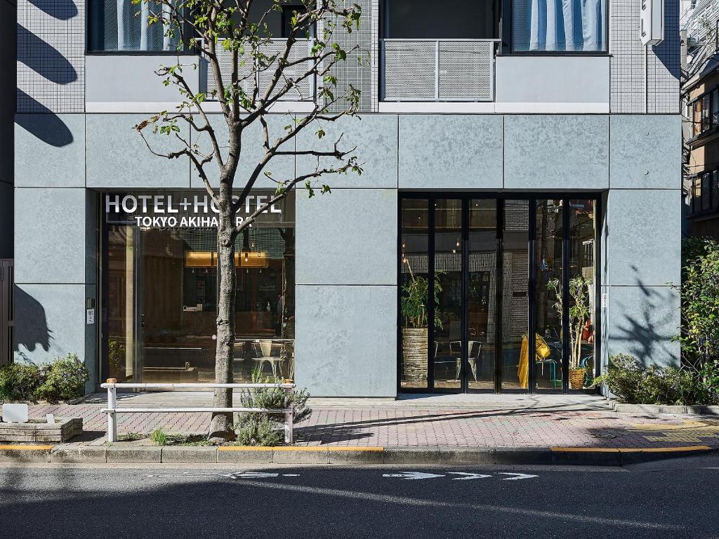 东京Hotel Plus Hostel TOKYO AKIHABARA的大楼前有树的酒店入口