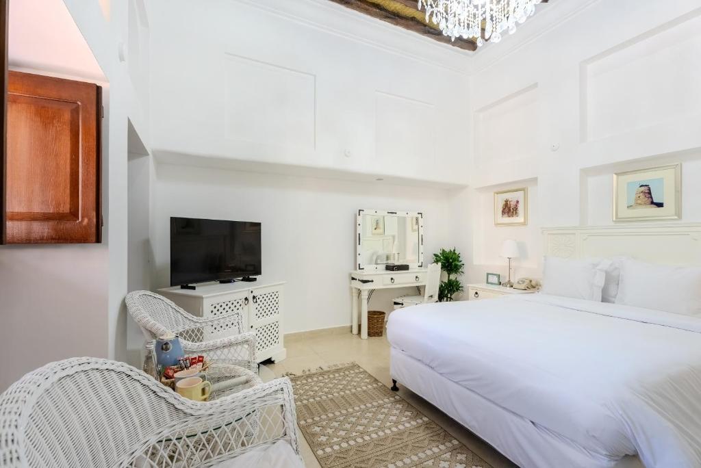 迪拜Arabian Boutique Hotel的一间白色卧室,配有床和电视