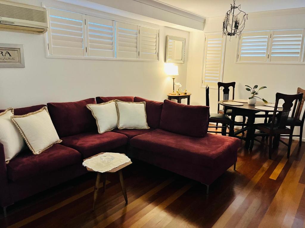 布里斯班Swan Guest House的客厅配有红色的沙发和桌子