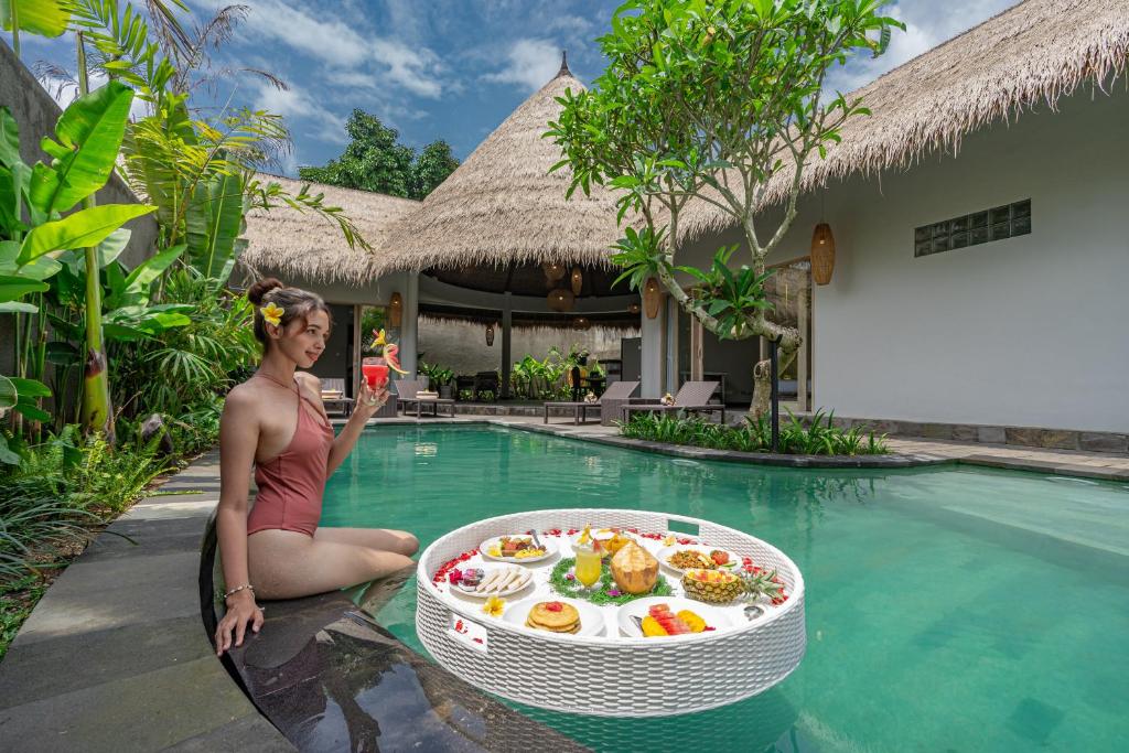 乌布Brand new Luxury 3BR villa Ethnic Ubud #3的坐在游泳池旁的女人,带上一盘食物