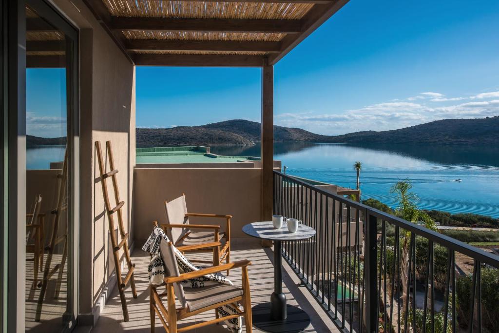 伊罗达Elounda Infinity Exclusive Resort & Spa - Adults Only的阳台配有桌椅,享有湖景