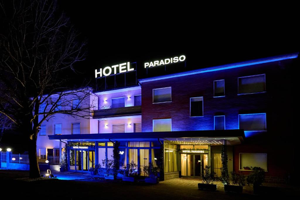 AltedoHOTEL PARADISO的一家晚上在旁边标有标志的酒店