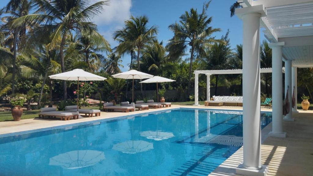 MaxaranguapeMaracajau Luxury Home - Villa-Mar-a-Villa的一个带椅子和遮阳伞的游泳池