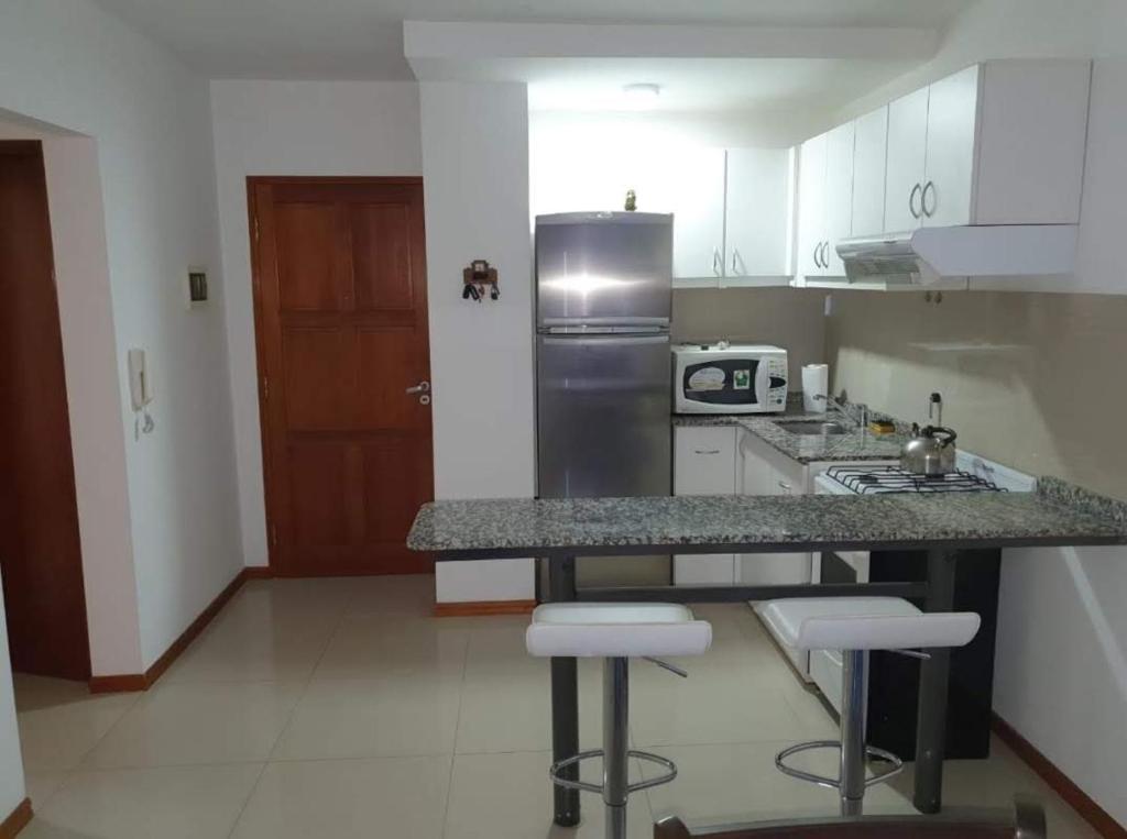 维拉卡洛斯帕兹Departamento San José IV- Villa Carlos Paz的厨房配有带凳子的柜台和冰箱。