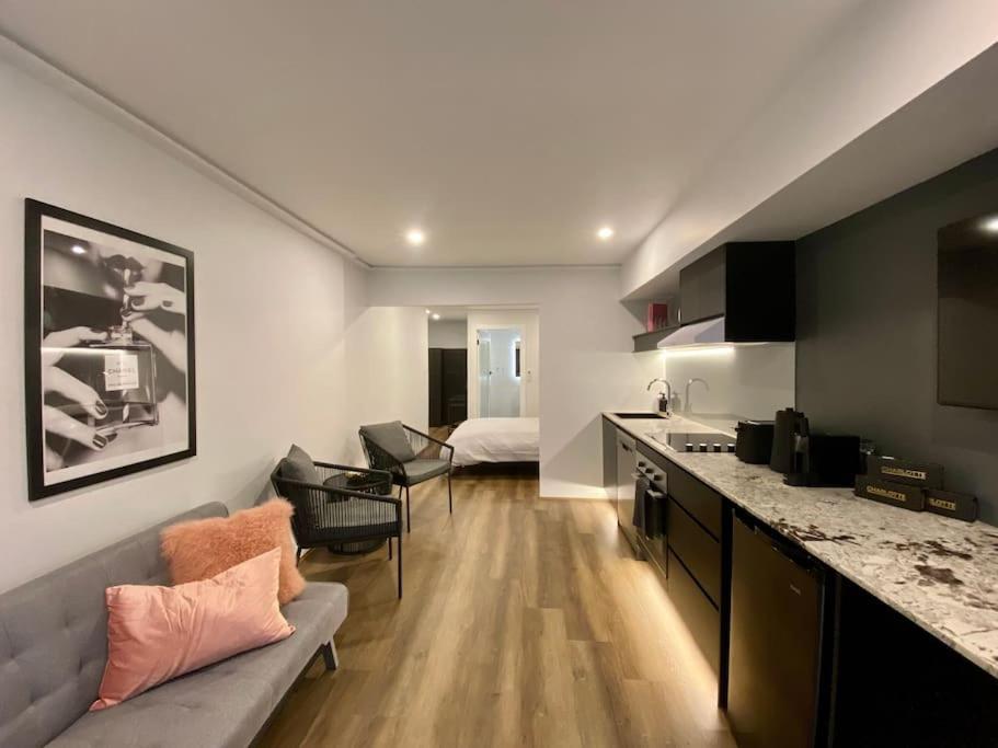 悉尼Luxury inner-west flat w/ breakfast and coffee included!的厨房以及带沙发和床的客厅。