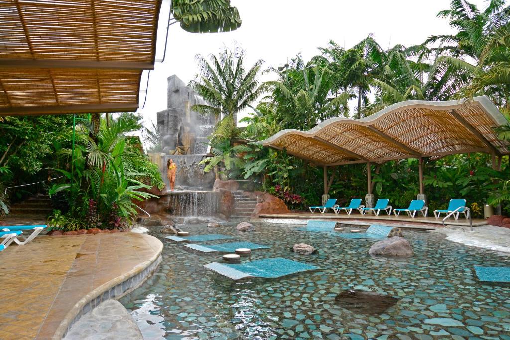 福尔图纳巴尔迪温泉酒店及Spa水疗中心的度假村内带椅子和瀑布的游泳池