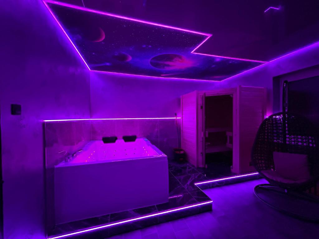 盖尔森基兴Wellness Suite mit Whirlpool und Sauna的一间设有紫色灯浴缸的客房