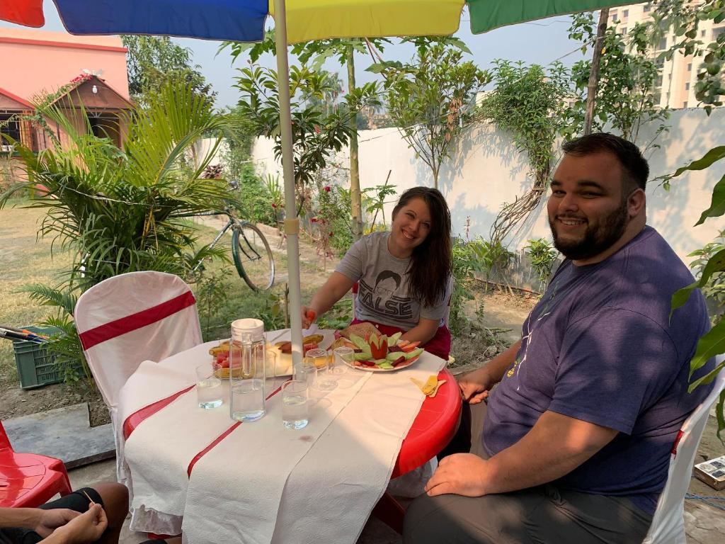 加尔各答Sarkar Villa Homestay的坐在餐桌上吃一盘食物的男人和女人