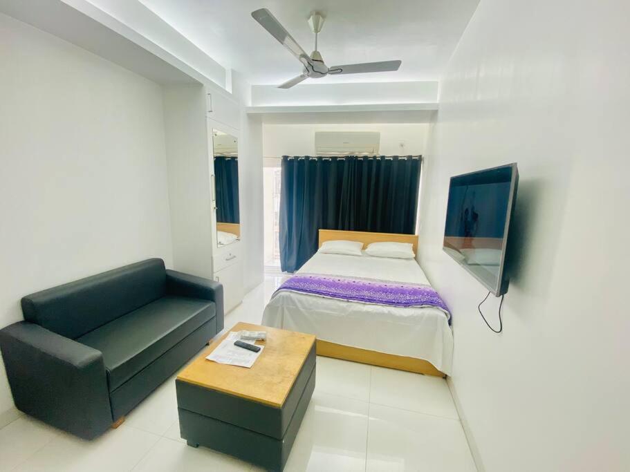 达卡Cozy Studio Apartment Basundhara的一间卧室配有一张床、一把椅子和一张沙发