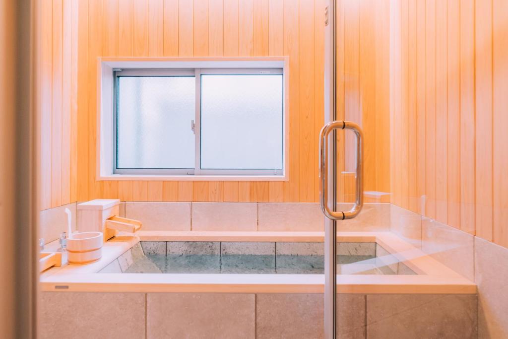 东京One Harajuku: Private Oasis的带浴缸和窗户的浴室