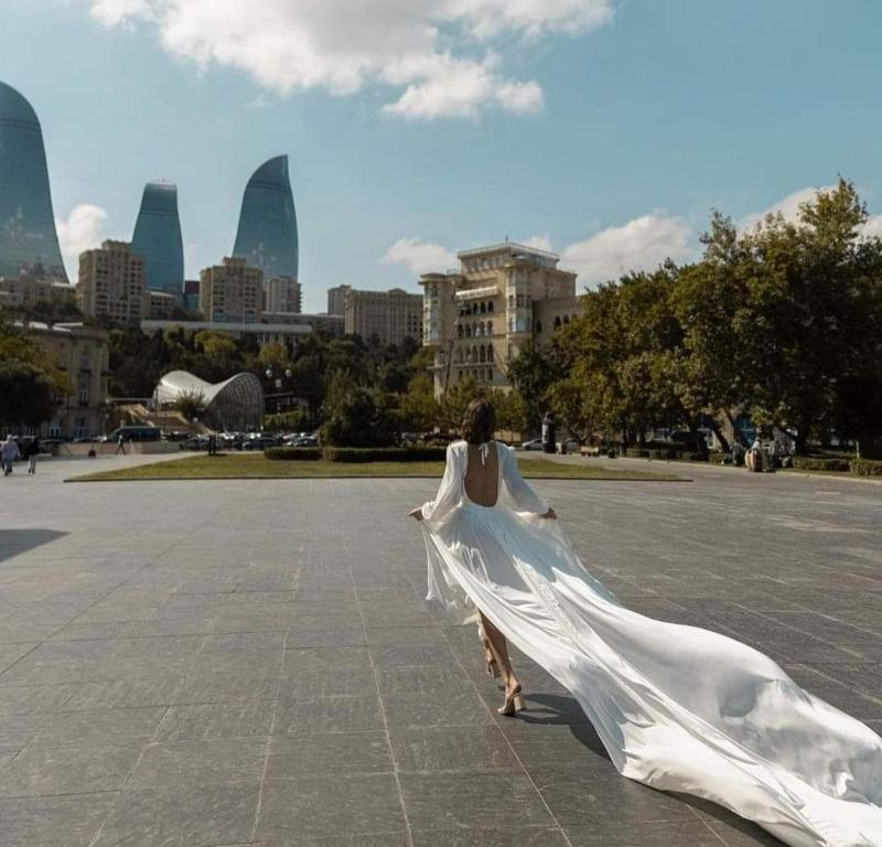 巴库Eminera Hostels Baku的穿白色衣服的妇女,在城市前走