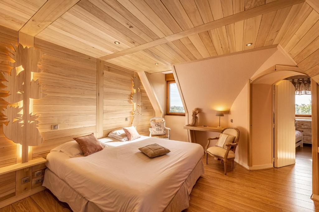 PailherolsLes Maisons de Montagne - Chez Marie的一间带一张大床的卧室,位于一个拥有木制天花板的房间