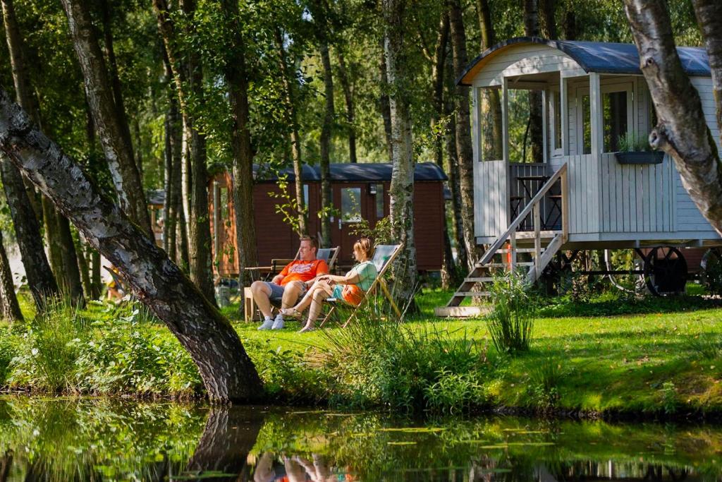 金洛伊Glamping Limburg - Back To Nature Experience的坐在小屋附近长凳上的男女