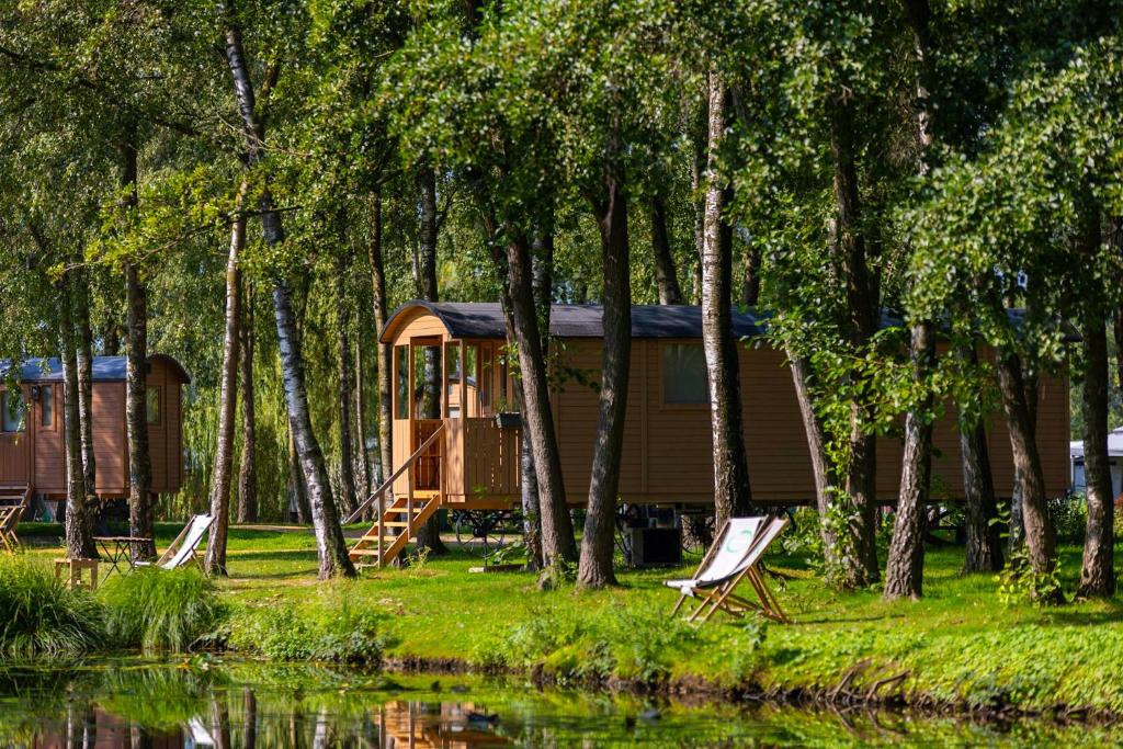 金洛伊Glamping - 25 min Roermond, Maasmechelen & Maastricht的湖畔的小屋,配有椅子