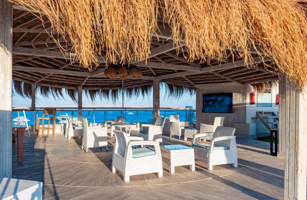赫尔格达Redcon Suites的一间设有白色椅子的餐厅,享有海景