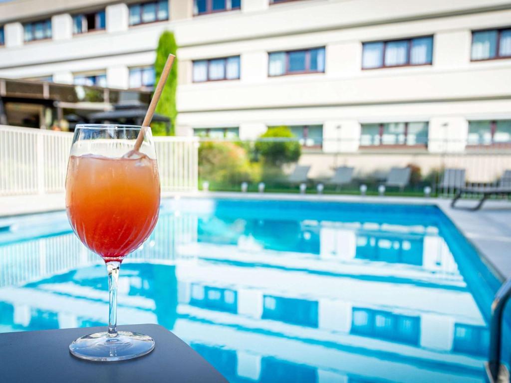 科累堑诺沃特玛娜瓦雷克雷吉安酒店的坐在游泳池旁的桌子上喝一杯