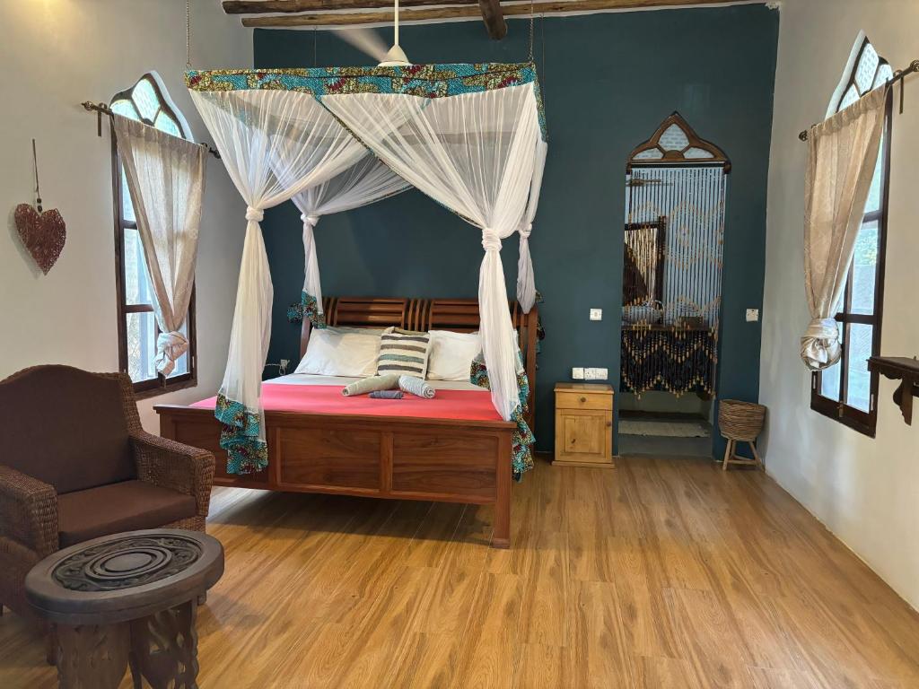 米查维Dreamland Bungalows Michamvi Kae的一间卧室配有一张天蓬床和一把椅子