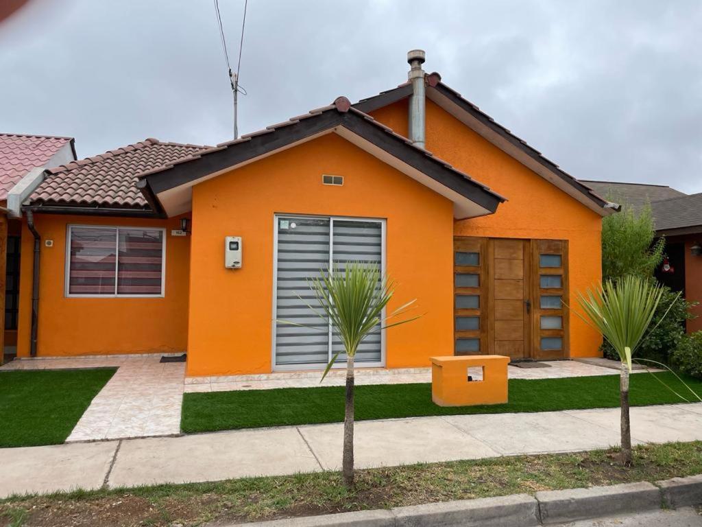 拉塞雷纳Amplia Casa en Condominio的一座橘子房子,前面有两棵棕榈树