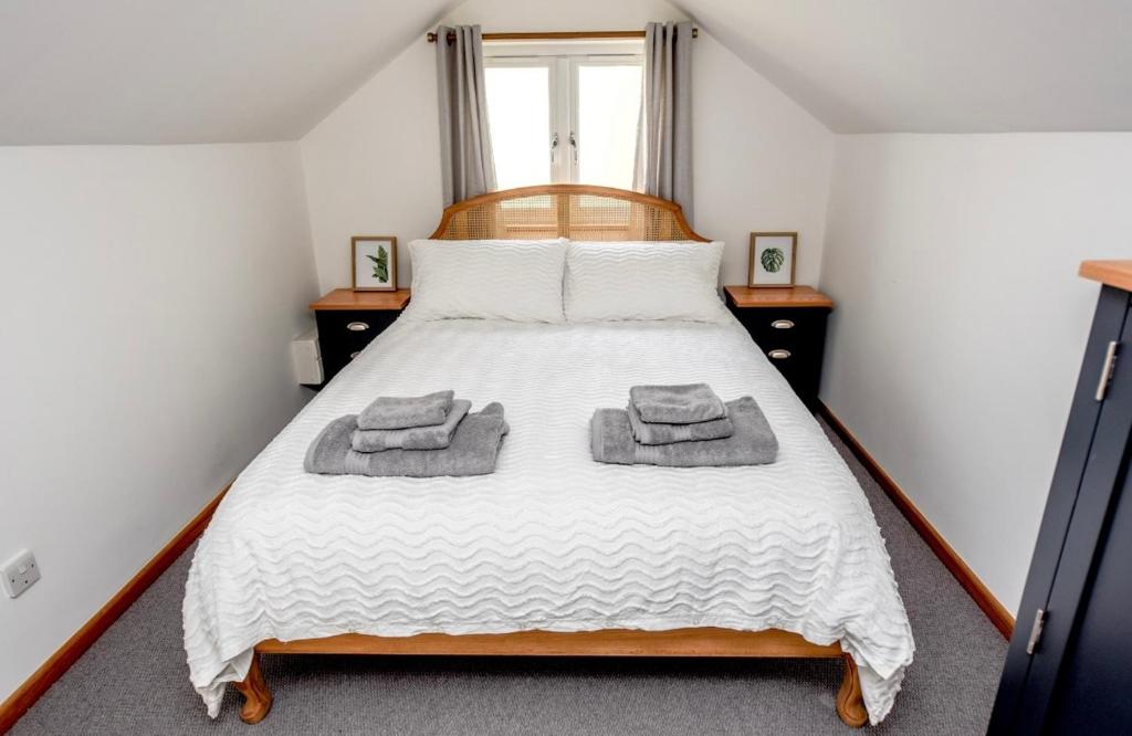 Temple EwellWoodman's Cottage的一间卧室配有一张床,上面有两条毛巾