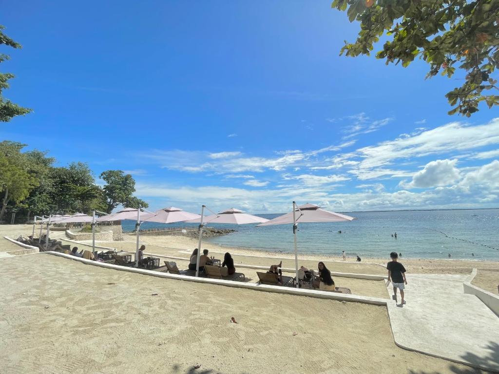 Lapu Lapu CityThe Beach Suite at The Mactan Newtown的一群人坐在海滩上,拿着遮阳伞