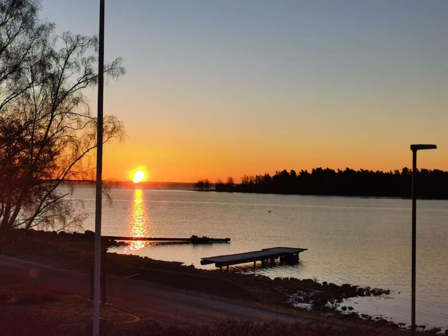 卡尔马Gästhus nära havet的日落时分坐在湖中的一个长凳