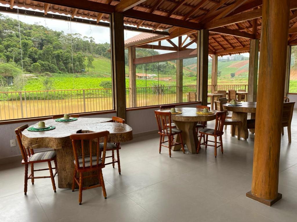 佩德拉阿祖尔Pousada Rural Recanto do Lago的用餐室设有桌椅和窗户。