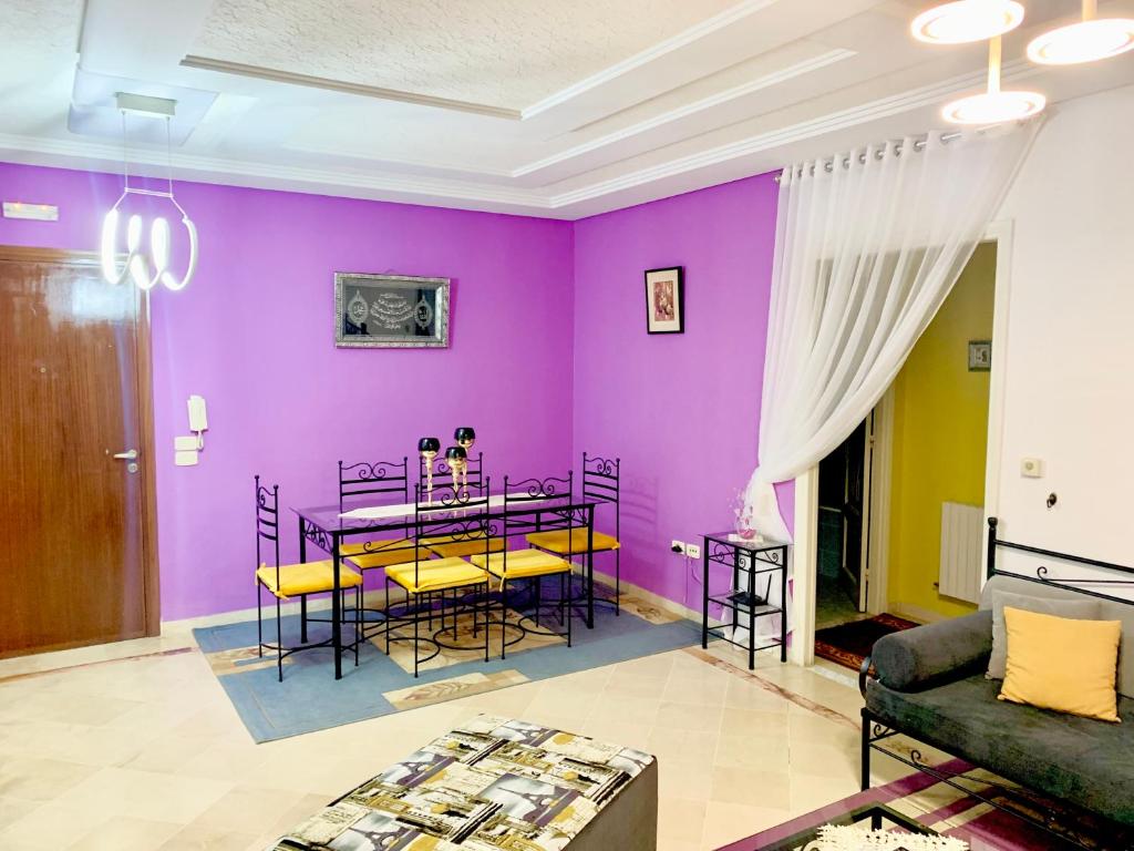 突尼斯Dream Appartement El Aouina的客厅设有紫色墙壁和桌椅