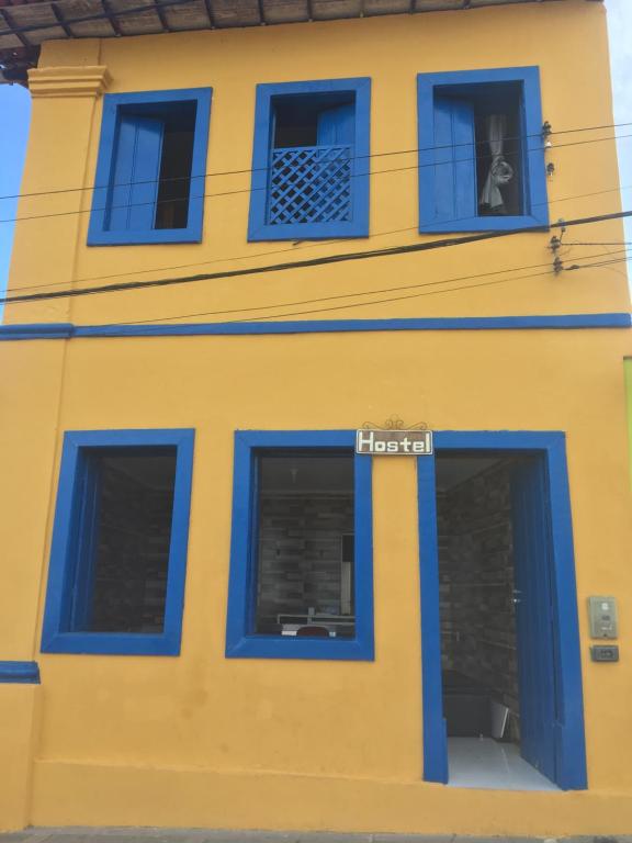 穆库热Hostel do Coreto的黄色的建筑,有蓝色的窗户和标志