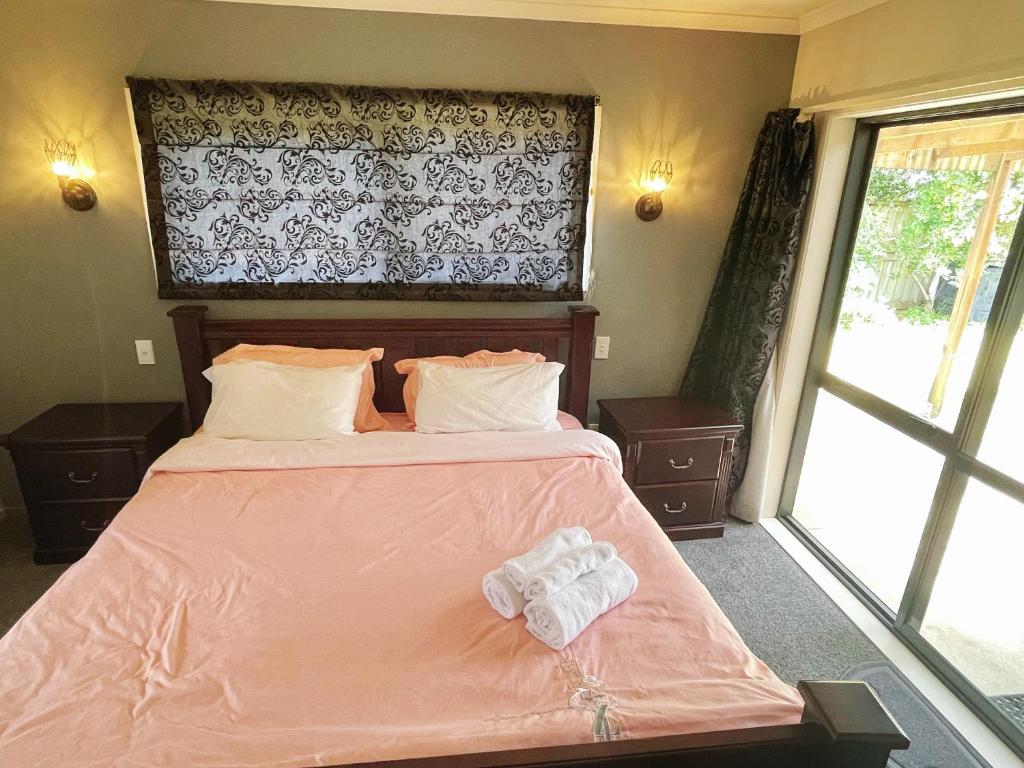 汉密尔顿Self checkin master room with private bathroom的一间卧室配有一张带粉色床单的床和一扇窗户。