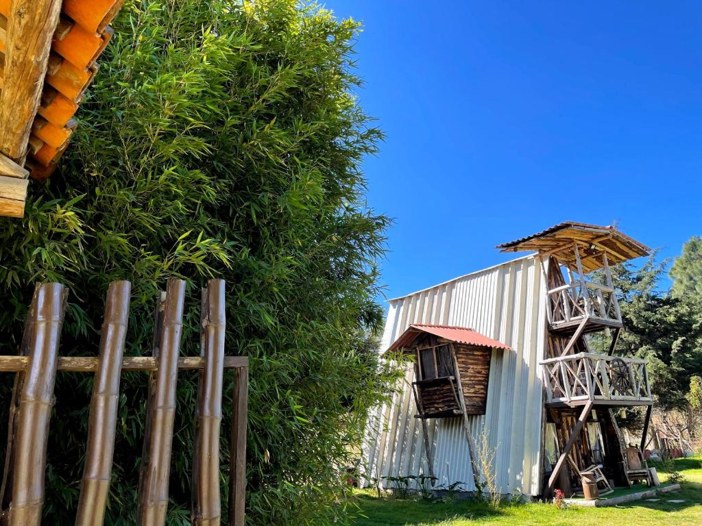 特克潘危地马拉Fuego - Wood Cabin Tecpan (No Wifi, Relax)的建筑物旁边的树边的栅栏