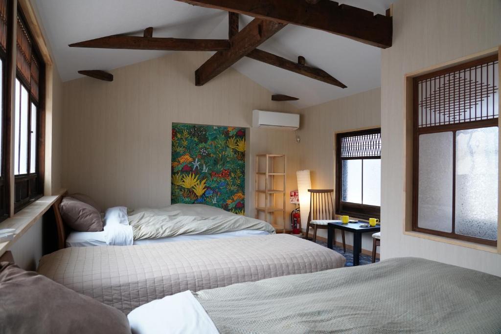 宫津市桜香楽　宮津町家　Sakara Miyazu-Machiya的一间卧室设有两张床,墙上挂着一幅画