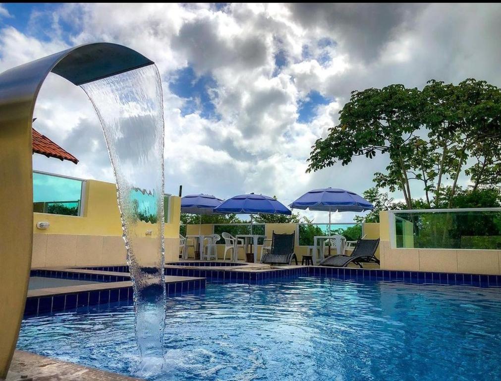 伊塔马拉卡Villa Velha Flats的游泳池中的喷泉,游泳池配有椅子和遮阳伞