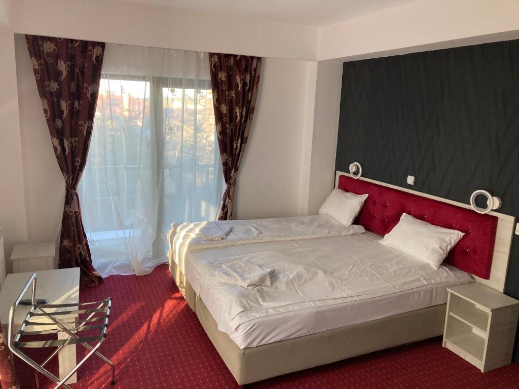 普雷代亚尔Hotel Rudo的一间卧室配有一张带红色床头板的床和窗户