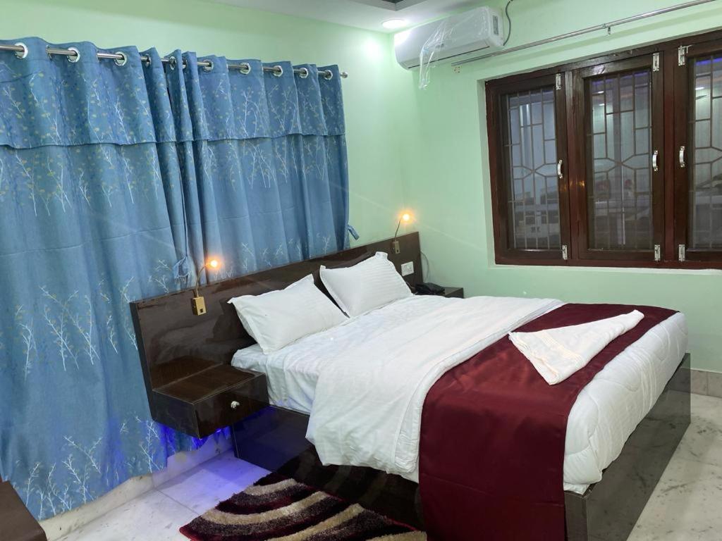比拉特纳加尔Royalwood City Inn的一间卧室配有一张带蓝色窗帘的大床
