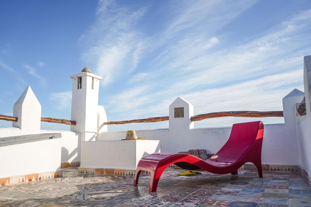 索维拉Dar 91 Essaouira的坐在白色建筑一侧的红色椅子