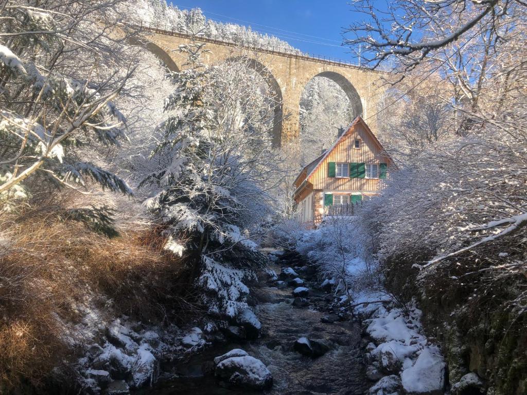 布莱特瑙Ravenna Lodge的一条小溪上的桥梁,在雪中有一所房子