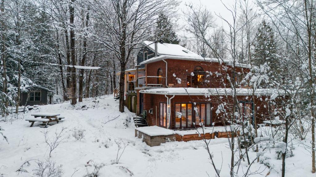 布罗姆湖Auberge Yoga Salamandre的雪地覆盖着房子,配有野餐桌