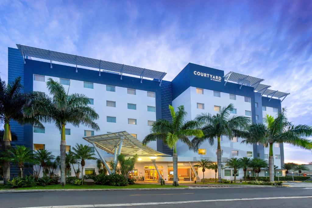 阿拉胡埃拉阿拉胡埃拉圣荷西机场万怡酒店的前面有棕榈树的酒店