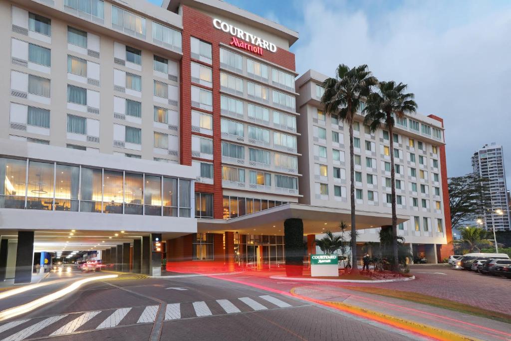 巴拿马城Courtyard by Marriott Panama Multiplaza Mall的一座酒店大楼,前面有棕榈树