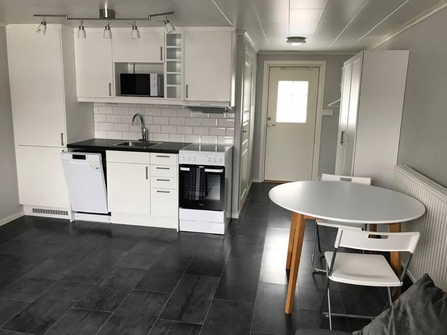 卡尔斯库加Lägenhet med uteplats的厨房配有白色橱柜和桌椅