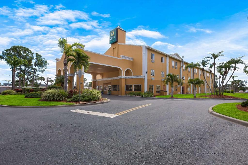 萨拉索塔Quality Inn Sarasota I-75的一座棕榈树环绕的大建筑,位于道路前