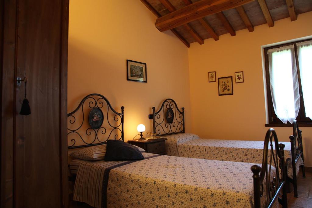 Monte GuiduccioAgriturismo Biologico Villa Rosa的一间卧室设有两张床和窗户。