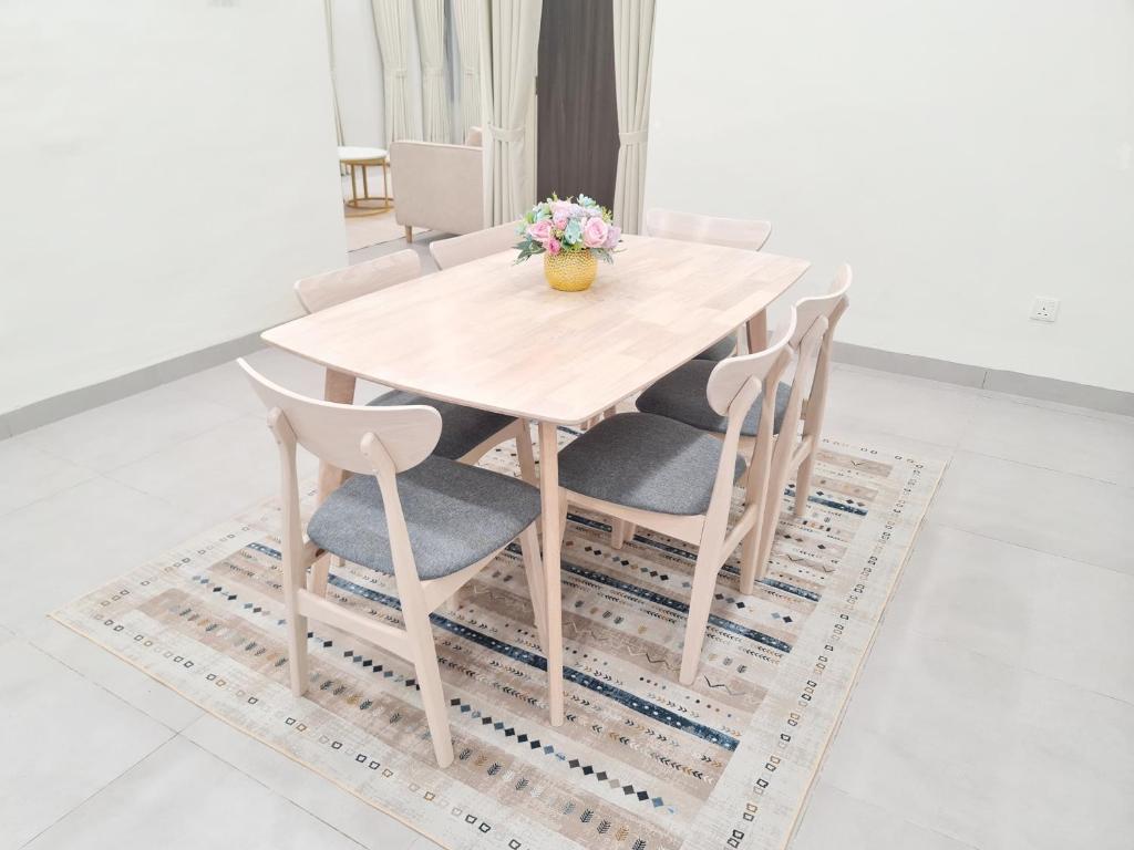 居林White Sweet Homestay, Kulim Hi-Tech Park Kedah utk MsIIim shj的木桌和椅子,花瓶