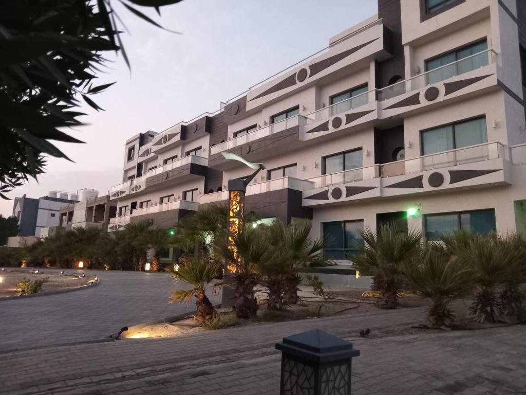 阿尔科兰Al Salam Resort的一座白色的大建筑,前面有棕榈树