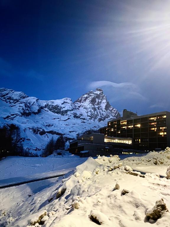 布勒伊-切尔维尼亚Ski paradise - Cielo alto Cervinia的一座雪地中的建筑,背景是一座山