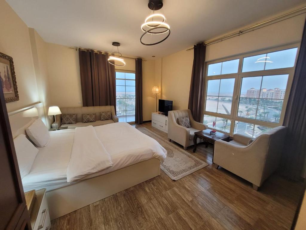阿卜杜勒国王经济城Lotus Apartments的一间卧室配有一张大床、一张沙发和椅子