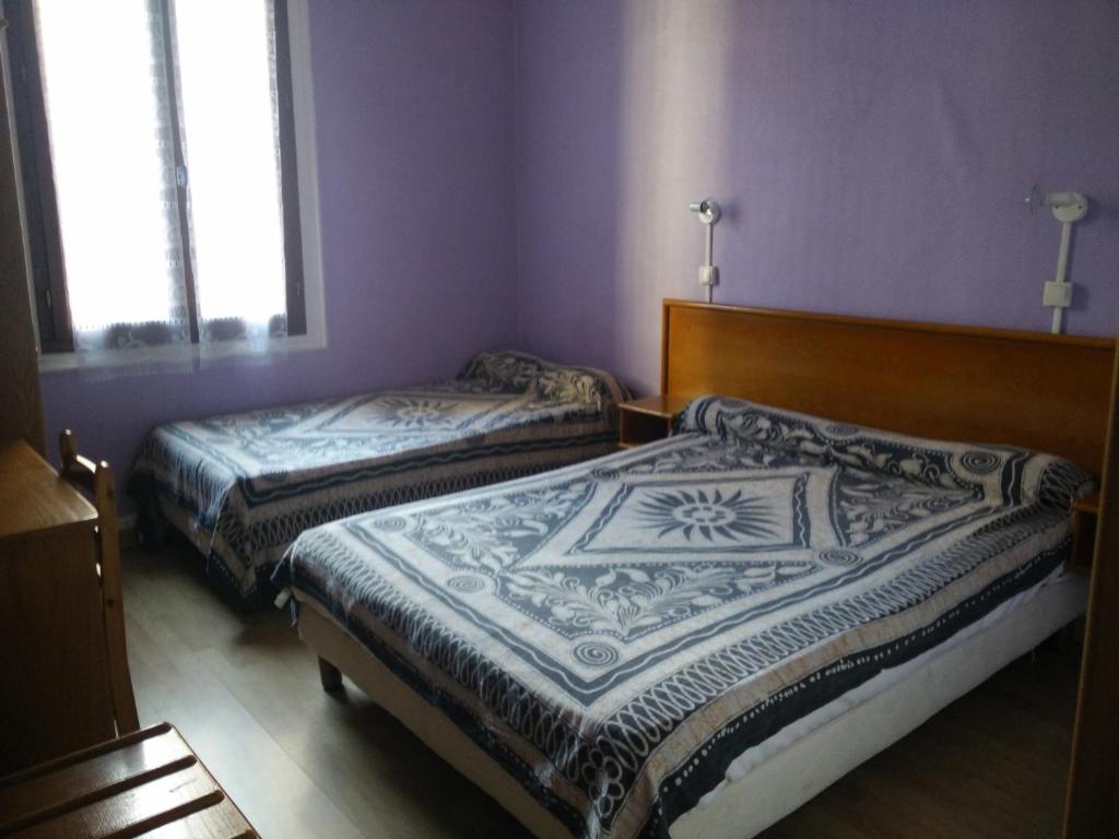 佩皮尼昂贝瑞酒店的紫色墙壁和窗户的客房内的两张床
