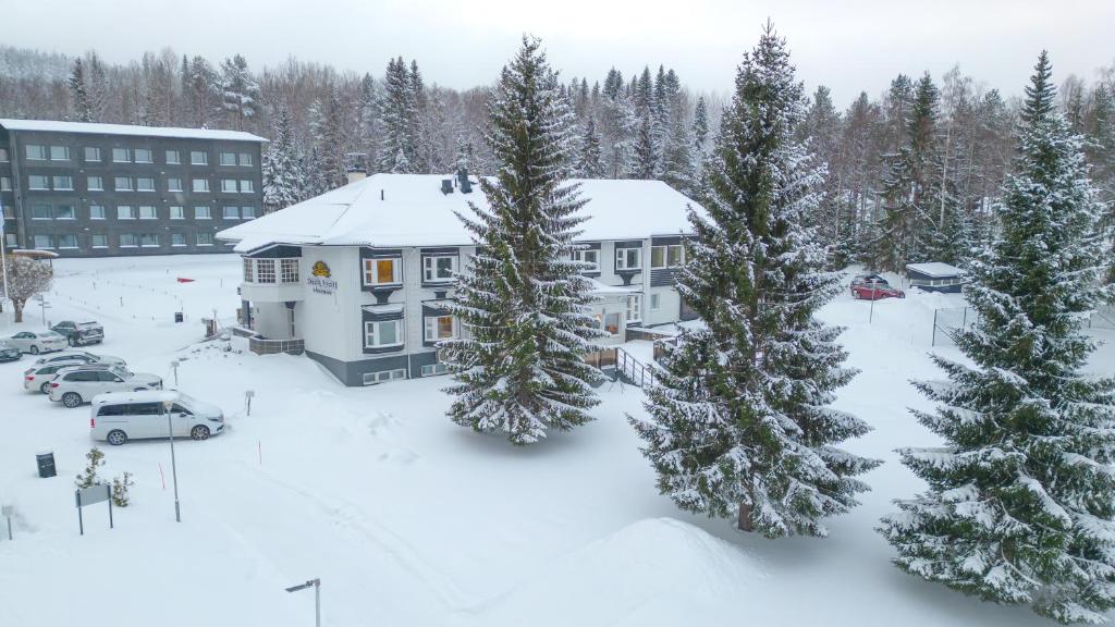 沃卡蒂Hotel Aateli Lakeside的公寓大楼拥有雪覆盖的树木和建筑