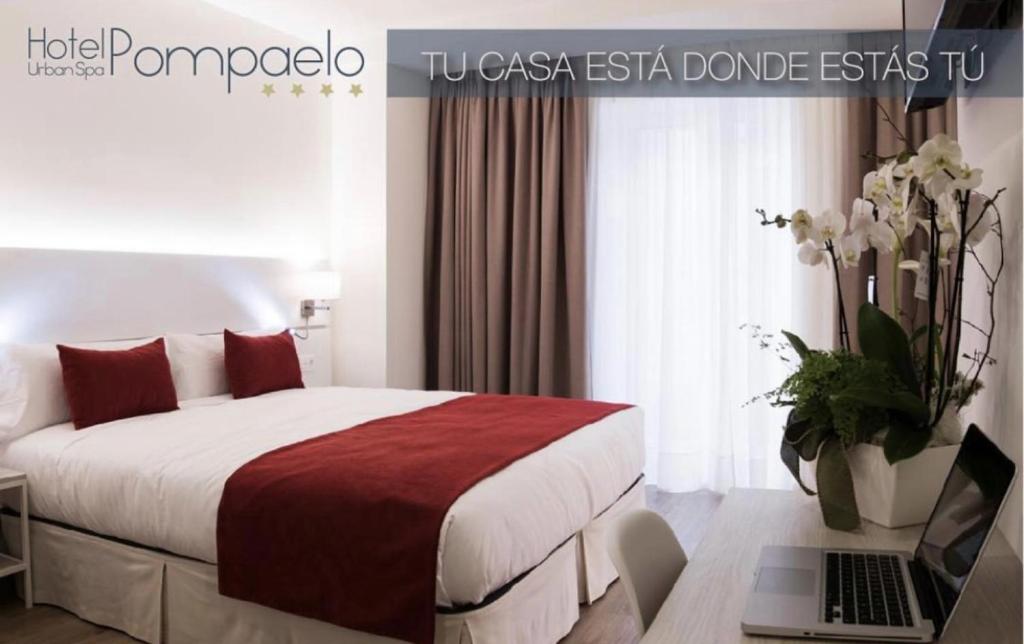 潘普洛纳Hotel Pompaelo Plaza del Ayuntamiento & Spa的一间卧室配有一张床和一张桌子上的笔记本电脑