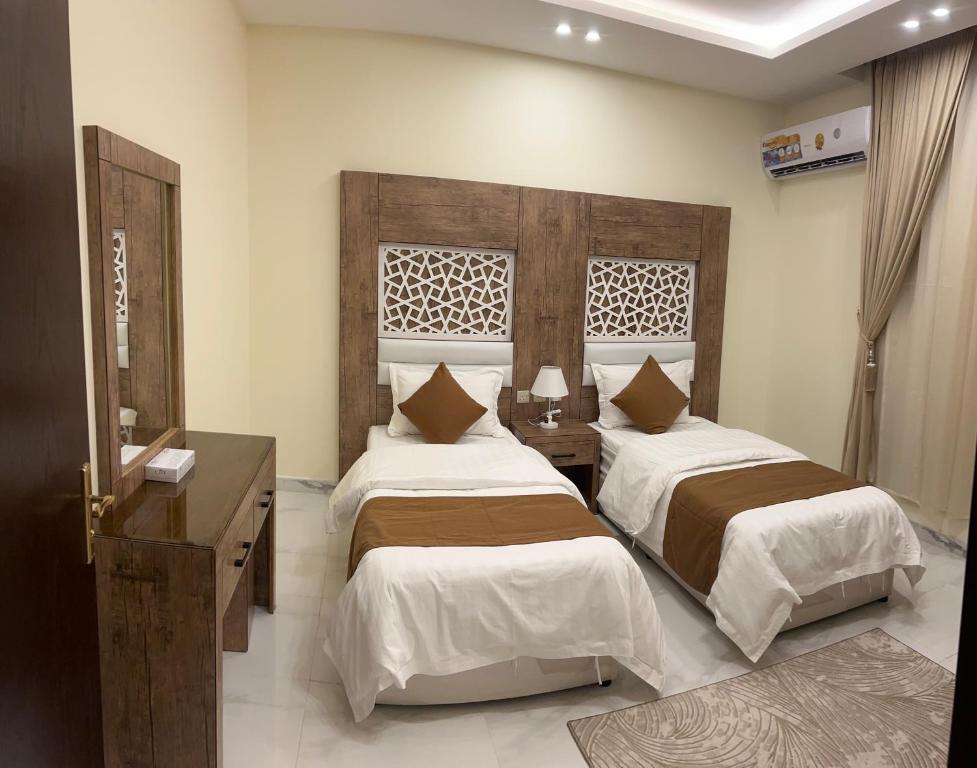 奈季兰كيان المخيم لشقق الفندقية的一间卧室设有两张床和木制床头板